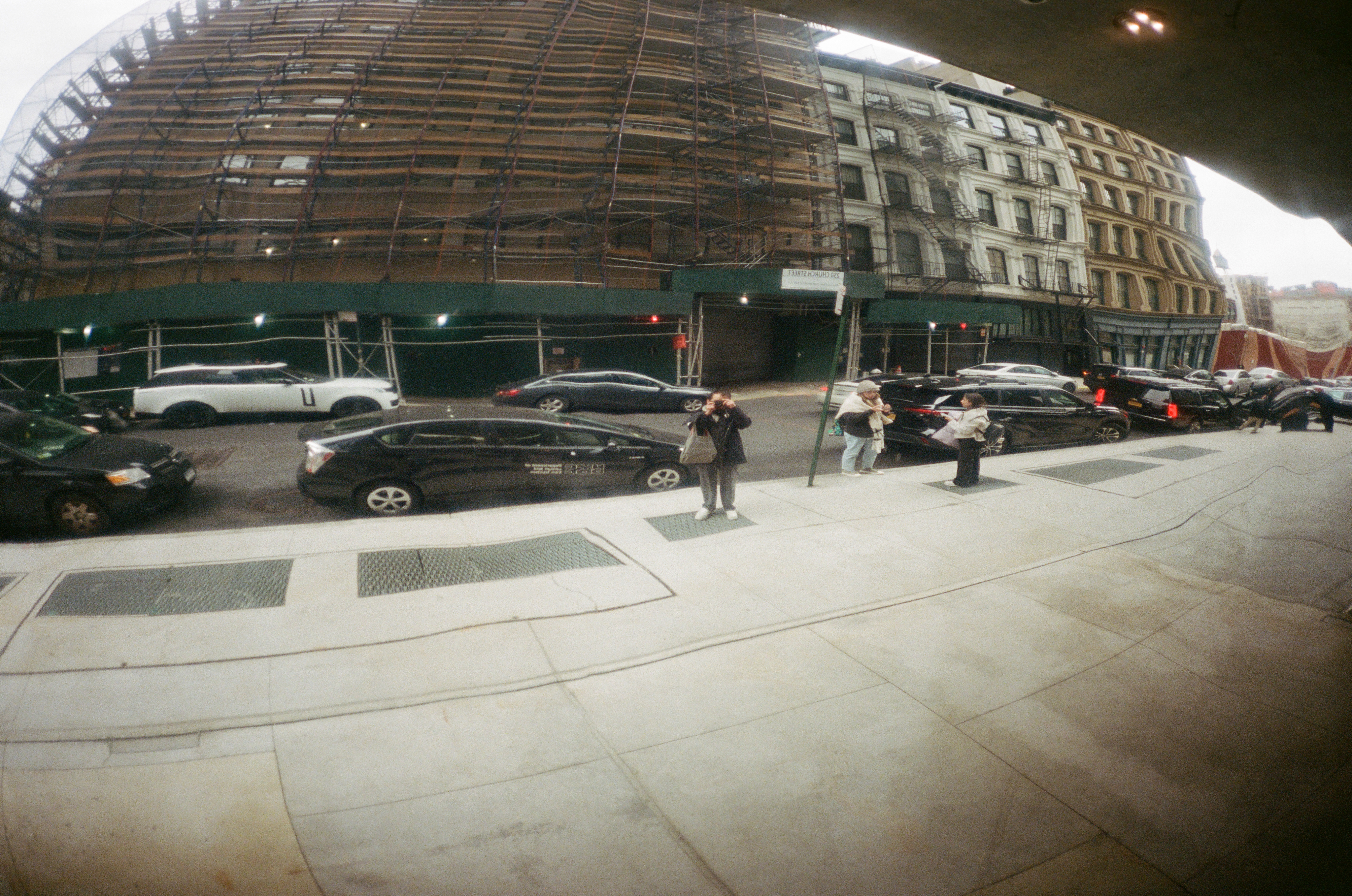 A wide-angle street scene beneath city scaffolding